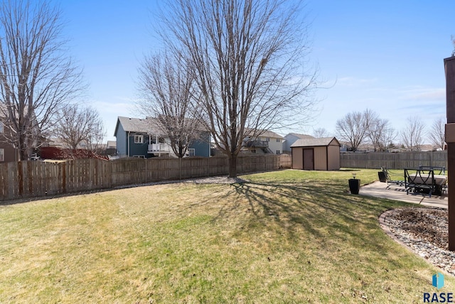 view of yard with a storage shed, a residential view, a fenced backyard, an outbuilding, and a patio area