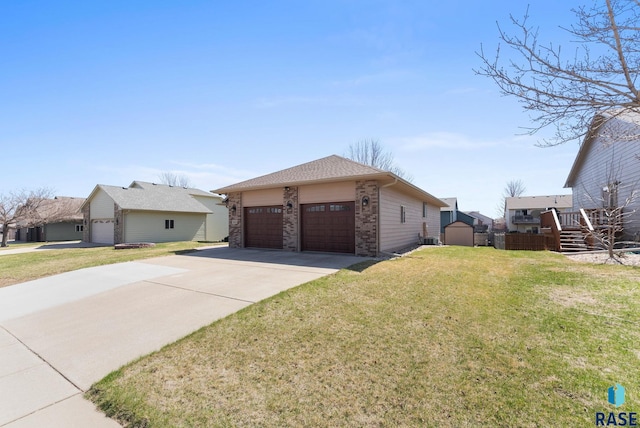 view of front of home featuring a storage unit, concrete driveway, a garage, an outbuilding, and a front lawn