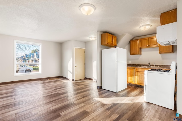 kitchen with freestanding refrigerator, a textured ceiling, gas range oven, and wood finished floors