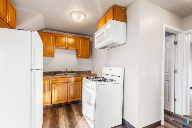 kitchen featuring a sink, dark wood-style flooring, a textured ceiling, and white appliances