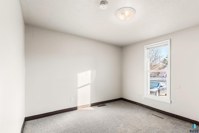 carpeted spare room with a textured ceiling, visible vents, and baseboards