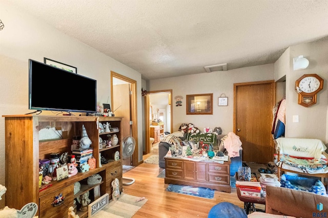 living room with a textured ceiling, light wood-type flooring, and visible vents