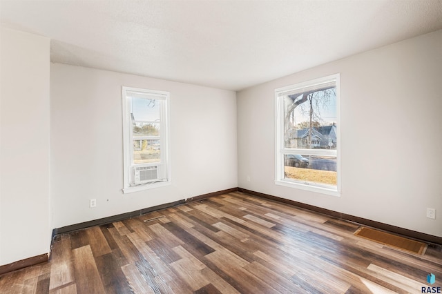 empty room featuring baseboards, cooling unit, and wood finished floors