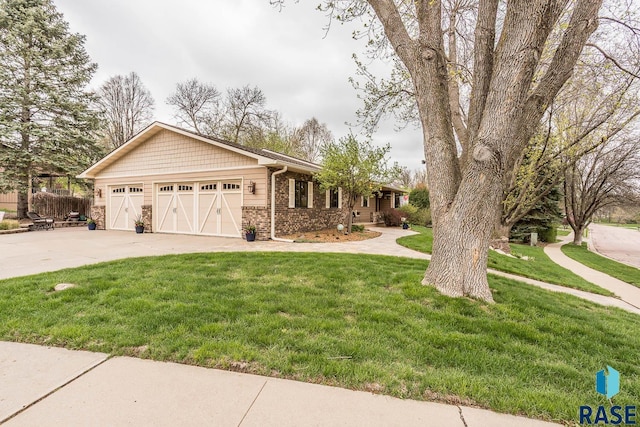 ranch-style home featuring concrete driveway, an attached garage, a front yard, and stone siding