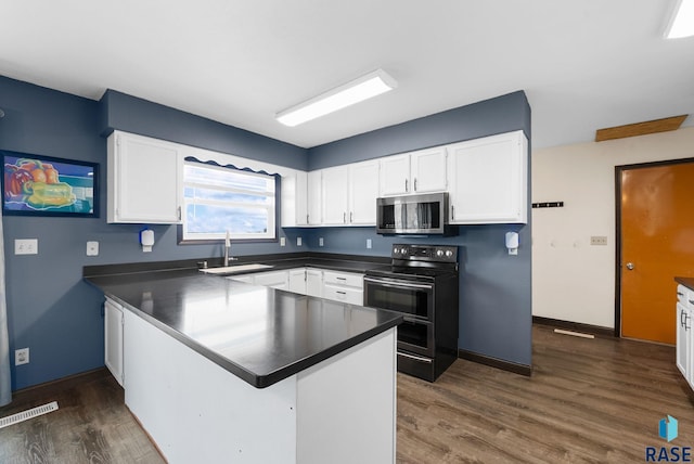 46902 284th St, Lennox, SD 57039 - kitchen with stainless steel microwave, a peninsula, a sink, range with two ovens, and dark countertops