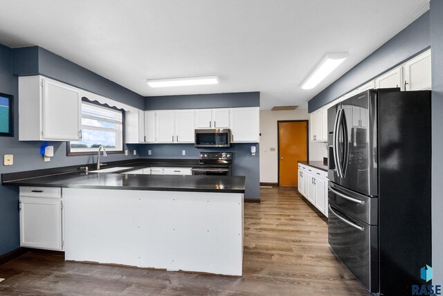 46902 284th St, Lennox, SD 57039 - kitchen featuring a sink, a peninsula, dark wood-type flooring, dark countertops, and stainless steel appliances