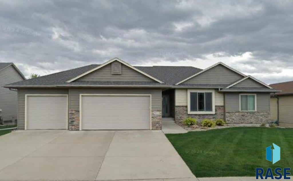 3713 E Steeple St, Sioux Falls, SD 57103 - craftsman-style house with an attached garage, concrete driveway, a front lawn, and stone siding