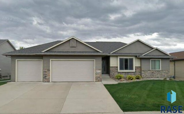 craftsman-style house with an attached garage, concrete driveway, a front lawn, and stone siding