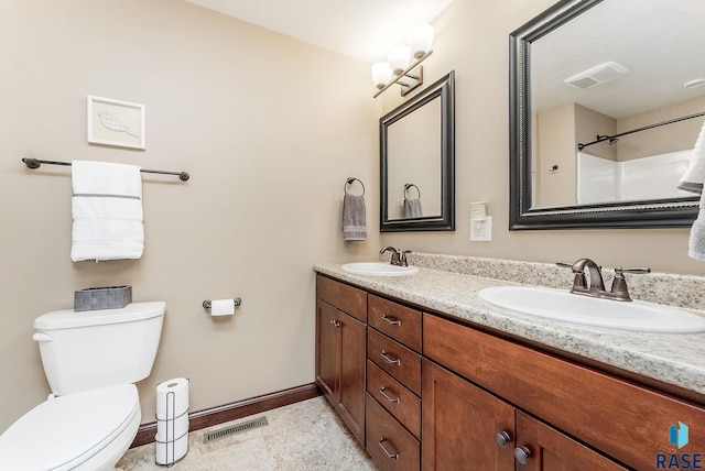 full bath with toilet, double vanity, and baseboards