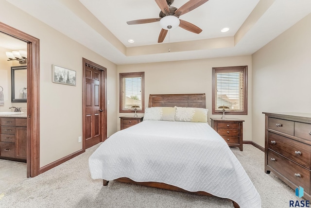 bedroom with light carpet, a sink, multiple windows, and baseboards