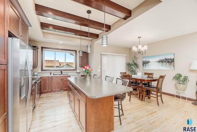 kitchen featuring appliances with stainless steel finishes, light wood-style floors, a kitchen island, a kitchen breakfast bar, and a sink
