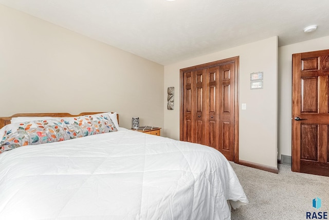 bedroom featuring light colored carpet, baseboards, and a closet