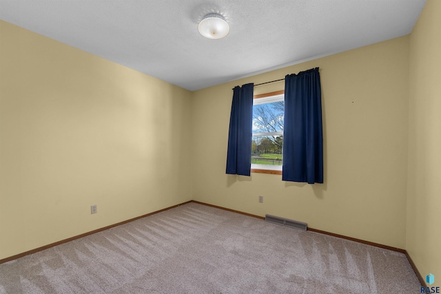 carpeted spare room featuring visible vents and baseboards