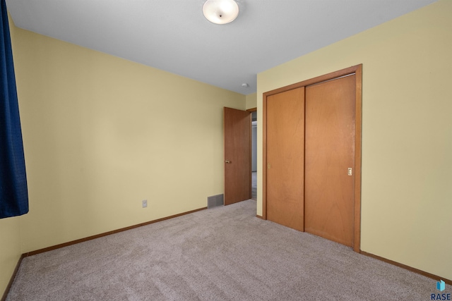 unfurnished bedroom with carpet flooring, a closet, baseboards, and visible vents