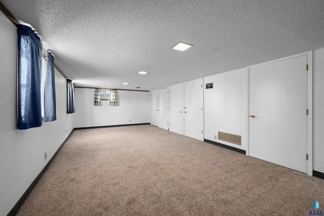 carpeted spare room with a textured ceiling, baseboards, and visible vents
