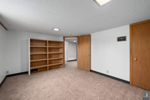 interior space featuring a textured ceiling, carpet, baseboards, and visible vents
