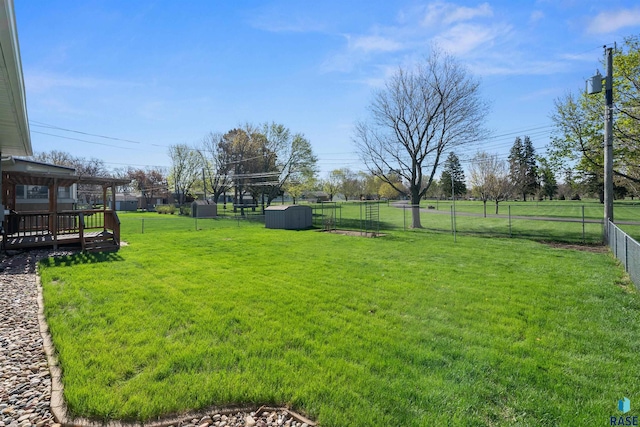view of yard featuring an outbuilding, a deck, a fenced backyard, and a shed