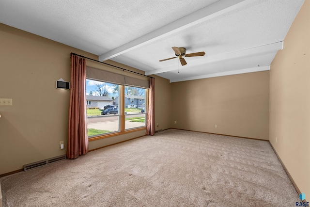 empty room with carpet, beam ceiling, visible vents, and a ceiling fan