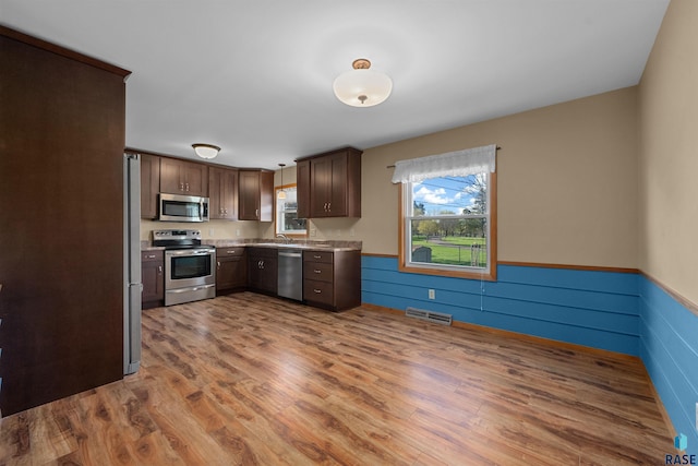 kitchen with wood finished floors, visible vents, light countertops, wainscoting, and appliances with stainless steel finishes