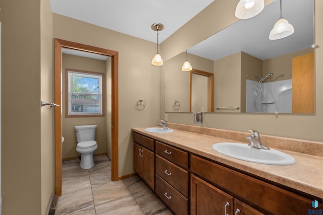 bathroom with toilet, baseboards, double vanity, and a sink
