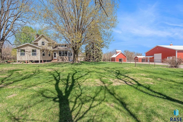 view of yard with an outbuilding, a pole building, fence, and a detached garage