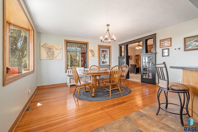 dining area with a chandelier, baseboards, light wood-type flooring, and visible vents