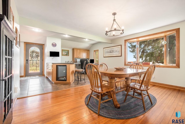 dining room with an inviting chandelier, wine cooler, baseboards, and light wood finished floors