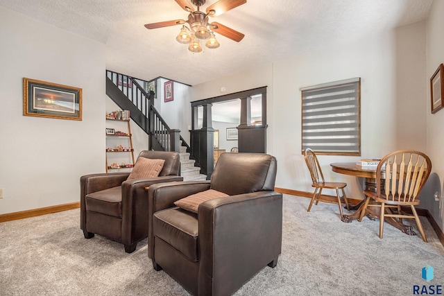 living area featuring a ceiling fan, stairs, light carpet, and baseboards