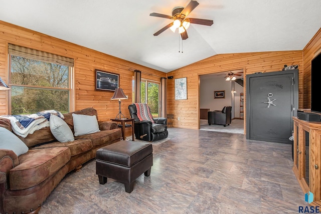living room featuring vaulted ceiling, ceiling fan, and wooden walls