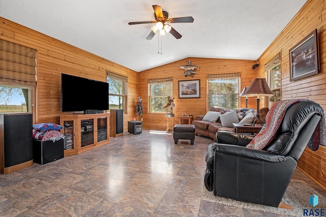 living area with vaulted ceiling, plenty of natural light, wood walls, and a ceiling fan