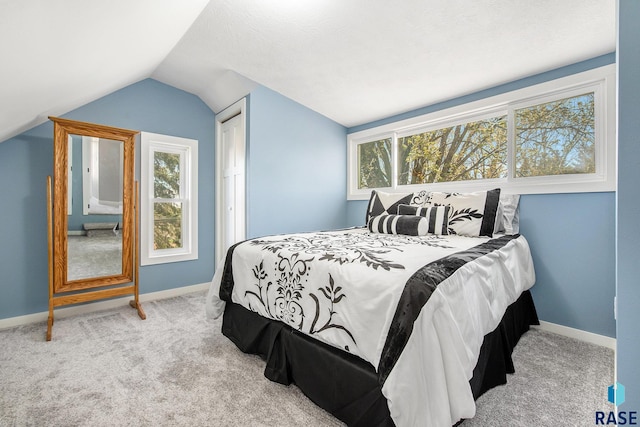 carpeted bedroom with vaulted ceiling and baseboards