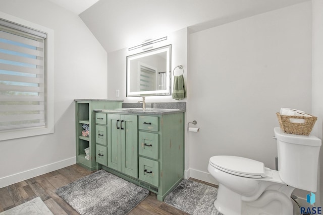 bathroom featuring toilet, vaulted ceiling, wood finished floors, and vanity