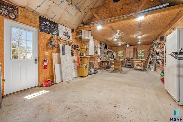 garage with freestanding refrigerator, ceiling fan, and a workshop area