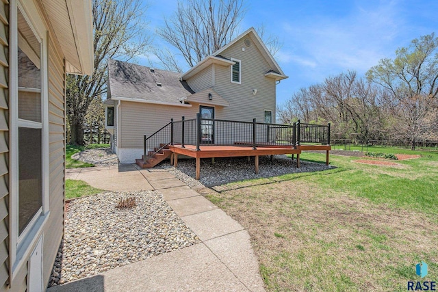 back of house featuring a yard, roof with shingles, and a deck