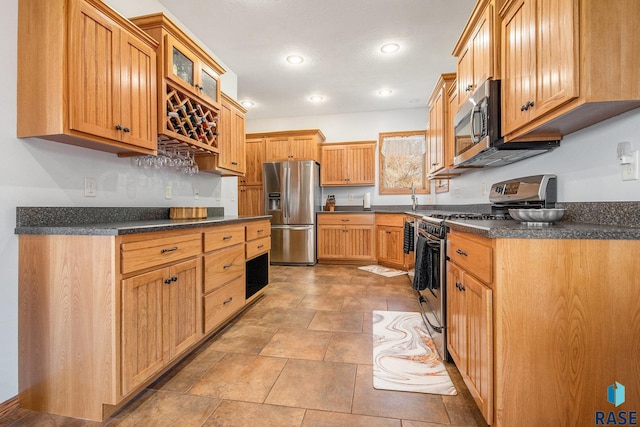 kitchen featuring recessed lighting, dark countertops, appliances with stainless steel finishes, and glass insert cabinets