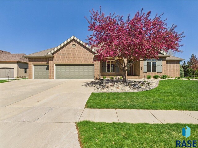 6204 S Doral Trl, Sioux Falls, SD 57108 - view of front of property with brick siding, an attached garage, concrete driveway, and a front lawn