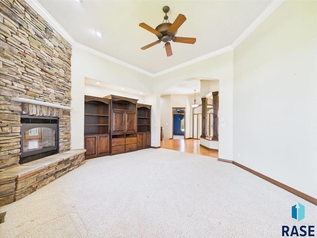 6204 S Doral Trl, Sioux Falls, SD 57108 - unfurnished living room featuring carpet floors, crown molding, arched walkways, baseboards, and a stone fireplace