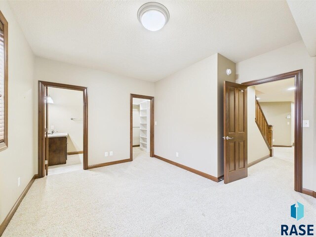 6204 S Doral Trl, Sioux Falls, SD 57108 - unfurnished bedroom featuring light colored carpet, baseboards, a spacious closet, a textured ceiling, and connected bathroom