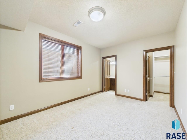 6204 S Doral Trl, Sioux Falls, SD 57108 - unfurnished bedroom featuring light colored carpet, baseboards, a spacious closet, a textured ceiling, and ensuite bath