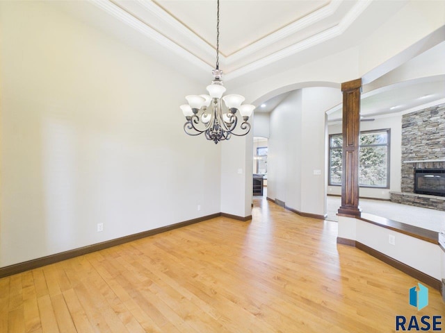 6204 S Doral Trl, Sioux Falls, SD 57108 - unfurnished dining area with crown molding, light wood-style floors, a stone fireplace, a raised ceiling, and arched walkways