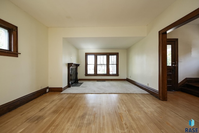 unfurnished living room with light wood-style flooring, a wealth of natural light, and baseboards