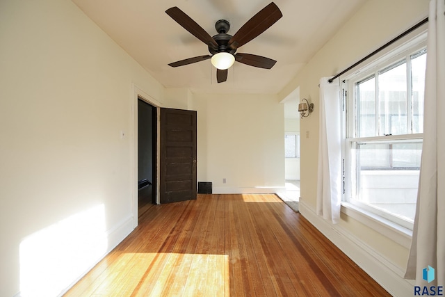 empty room with a ceiling fan, baseboards, and hardwood / wood-style flooring