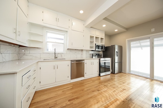 kitchen featuring a sink, tasteful backsplash, open shelves, white cabinetry, and appliances with stainless steel finishes