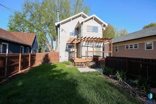back of property featuring a lawn, a wooden deck, a pergola, and a fenced backyard
