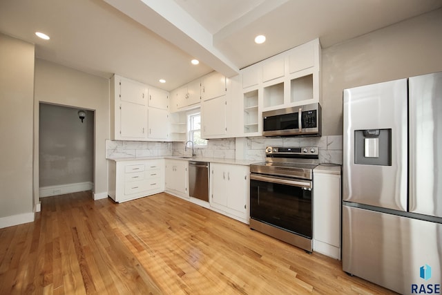 kitchen with baseboards, white cabinetry, backsplash, light countertops, and appliances with stainless steel finishes