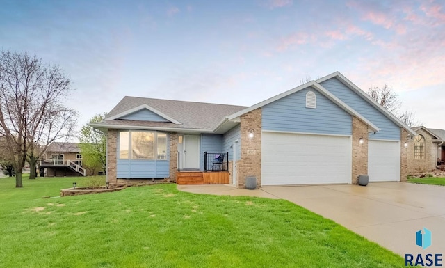view of front of home featuring an attached garage, concrete driveway, brick siding, and a front yard