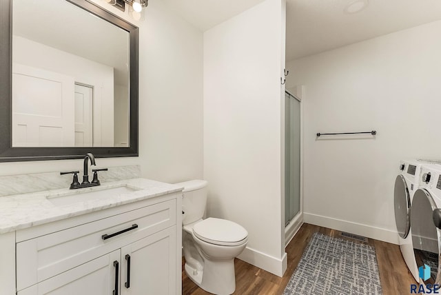 full bath with toilet, visible vents, a shower stall, wood finished floors, and separate washer and dryer