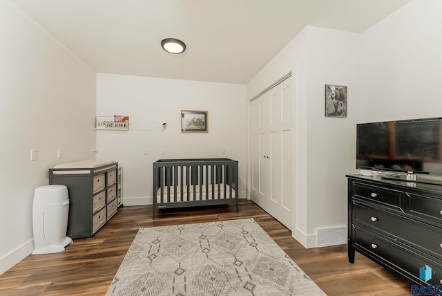 bedroom featuring dark wood-style flooring, baseboards, a closet, and visible vents