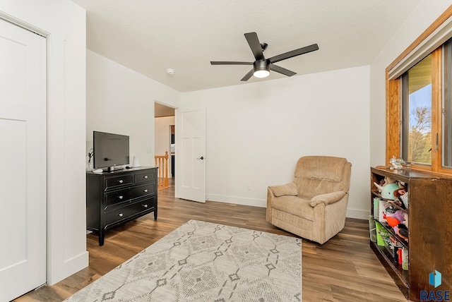 sitting room featuring a ceiling fan, baseboards, and wood finished floors