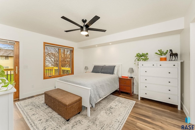bedroom featuring baseboards, multiple windows, and wood finished floors